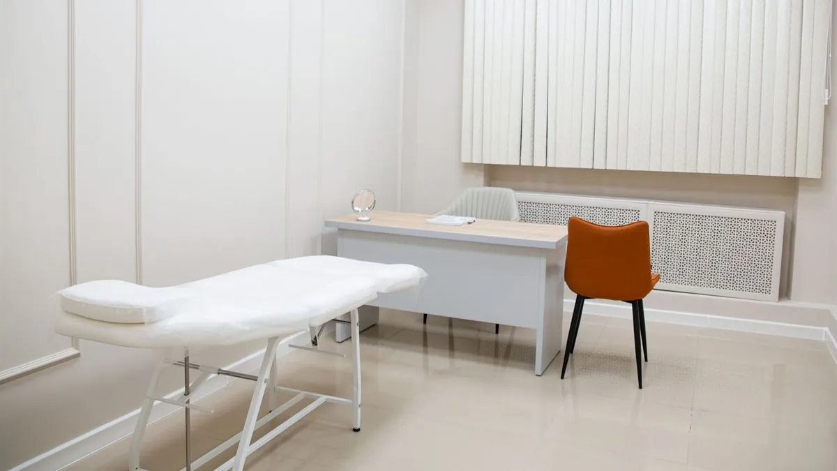 Empty medical consulting room with a desk, two chairs and an examination bed